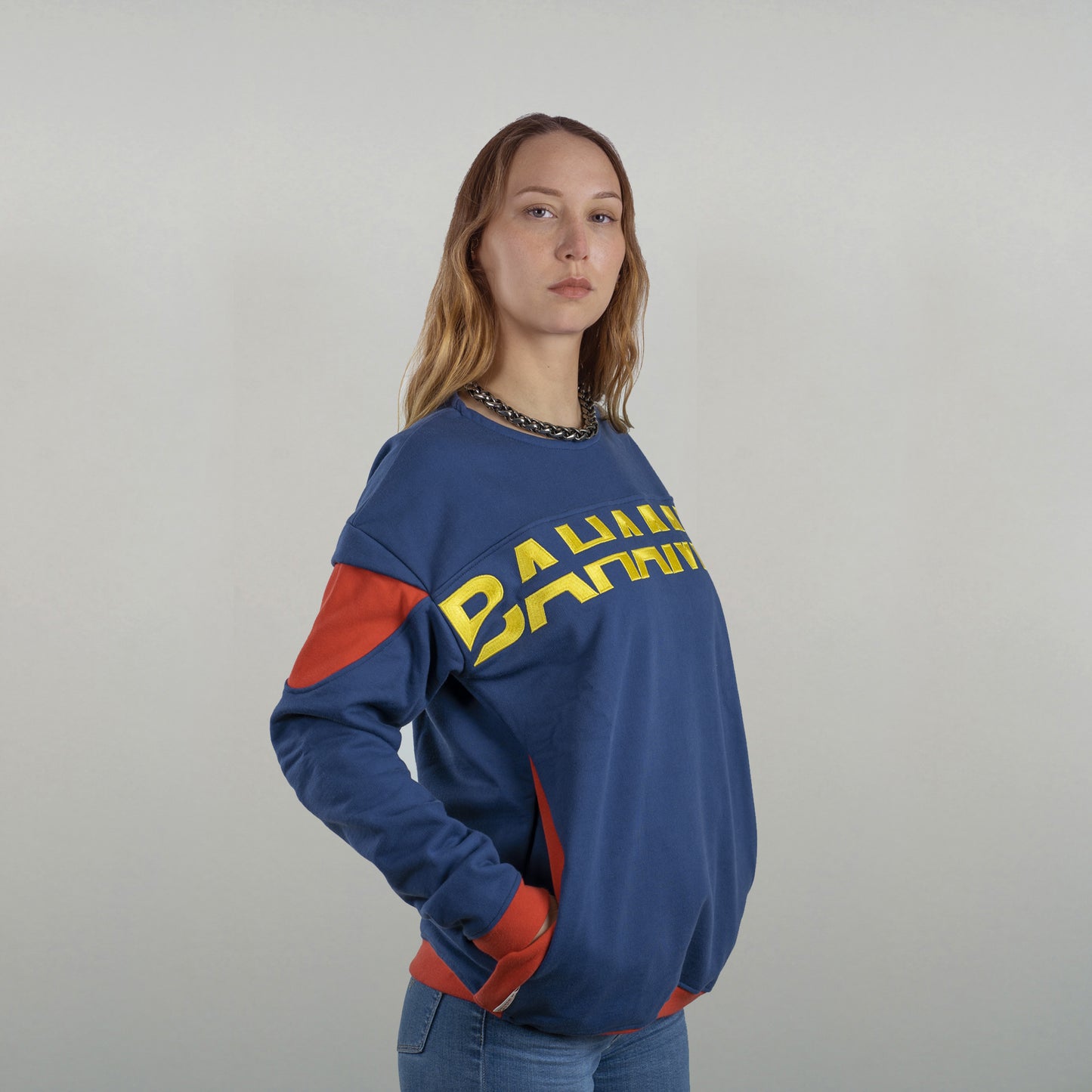 Le sweat est porté par un model féminin, vu de 3/4 face par la gauche (on discerne le début du logo brodé Bahamut)