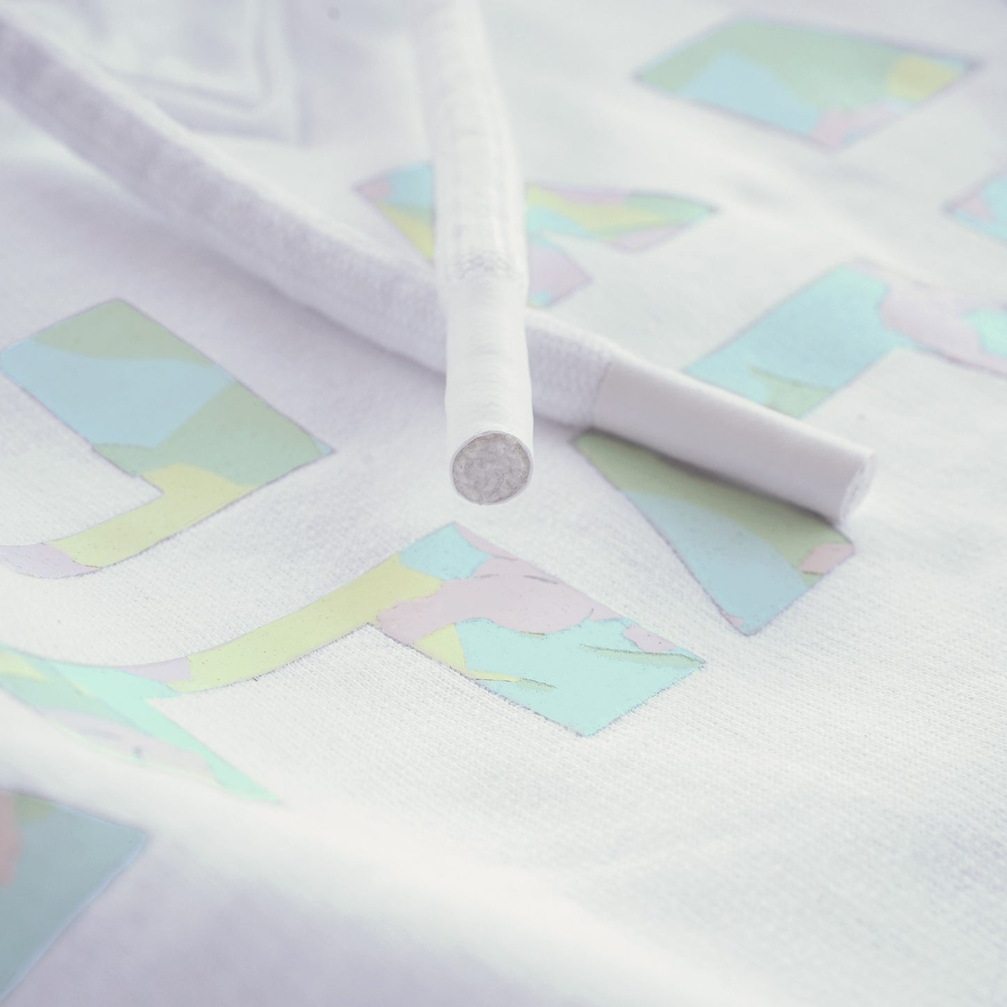 Gros plan sur l'impression du logo Bahamut en en camouflage pastels et sur les embouts des cordons épais.
