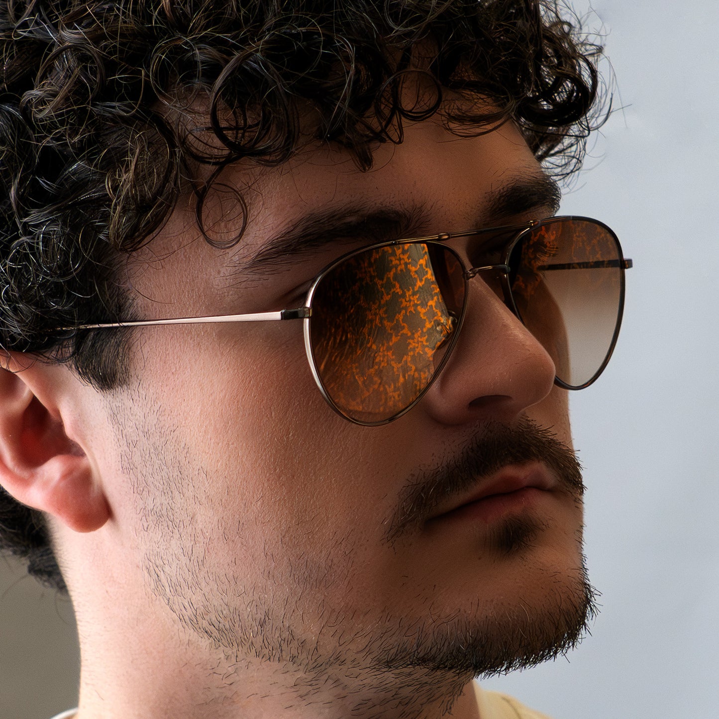 Gros plan sur "LES" Aviator, portées par un model masculin. Le monogramme apparait dans la lumière.