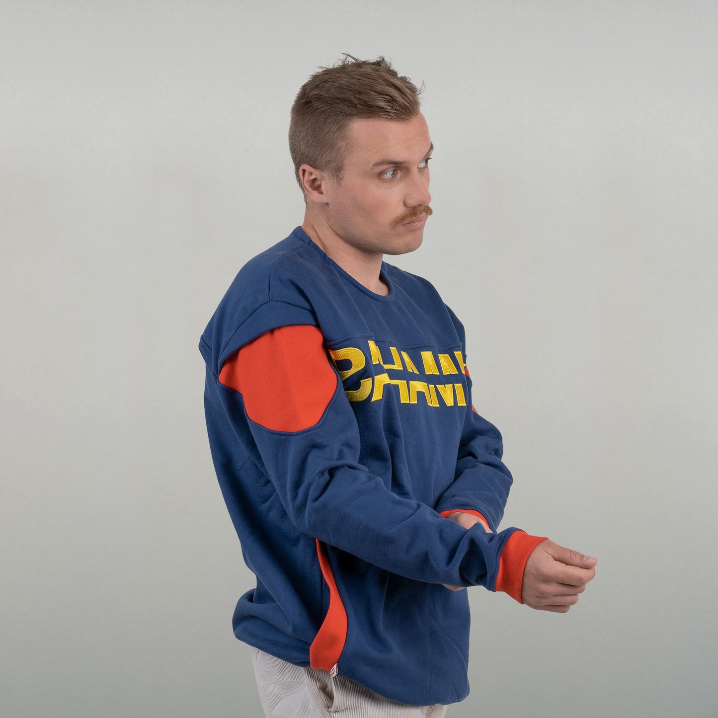 Le sweat est porté par un model masculin de 3/4. On voit parfaitement la découpe de l'épaule.