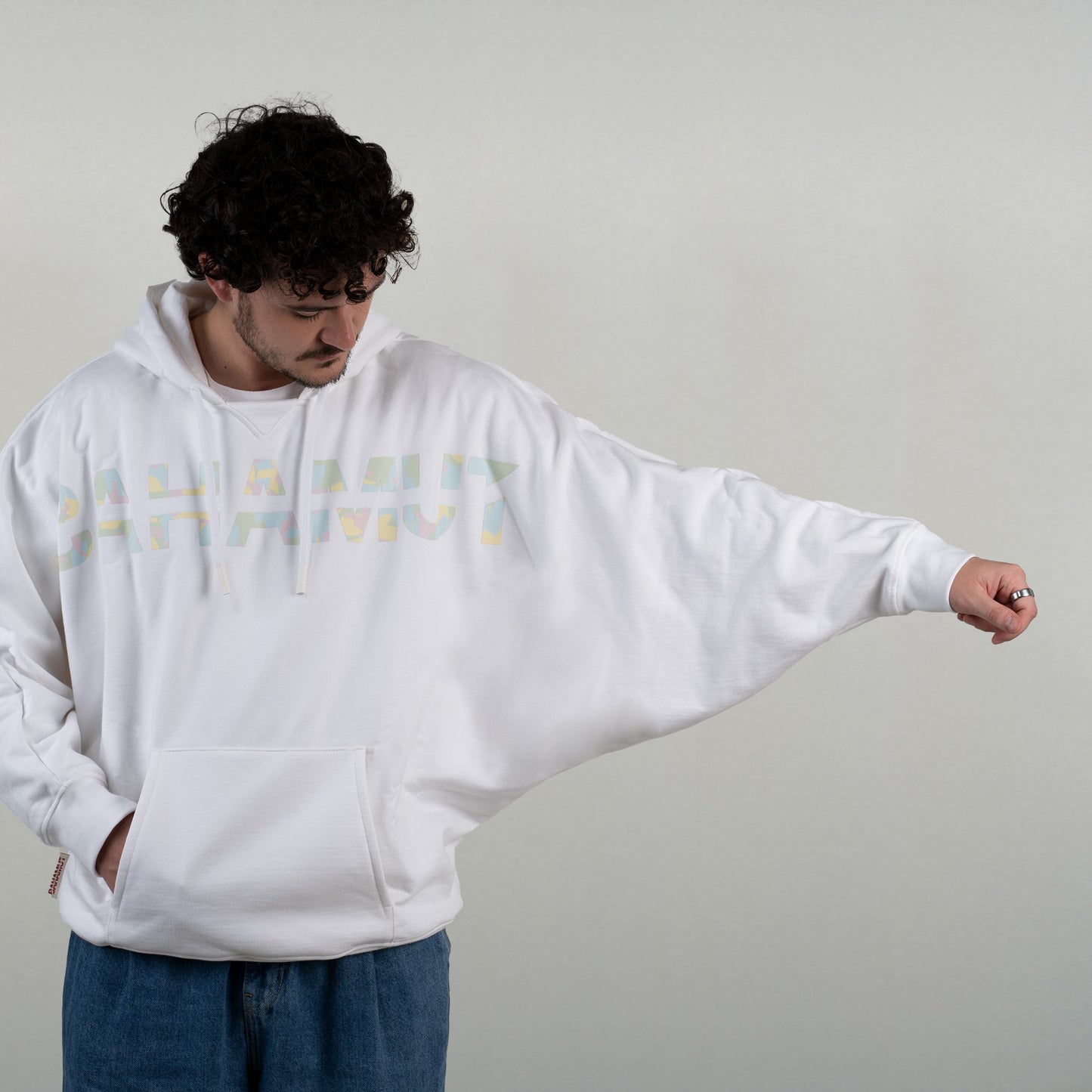 Le sweat est vu porté par un modèle masculin vu de face. Il tend son bras afin de montrer la manche chauve souris