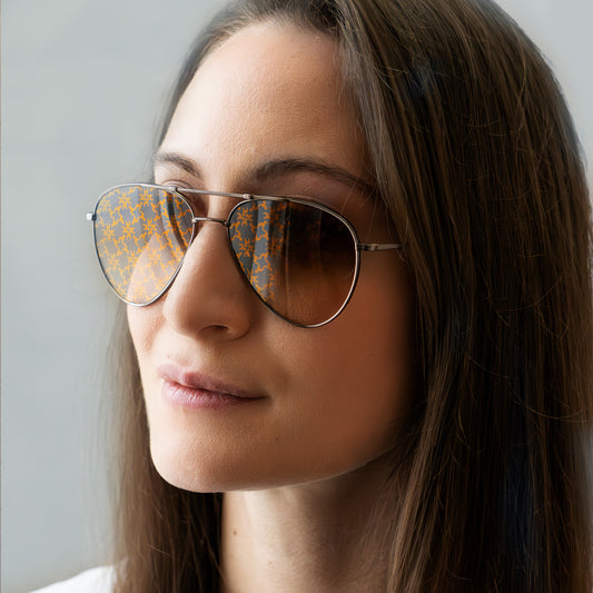 Gros plan sur "LES" Aviator, portées par un model féminin. Le monogramme apparait dans la lumière.